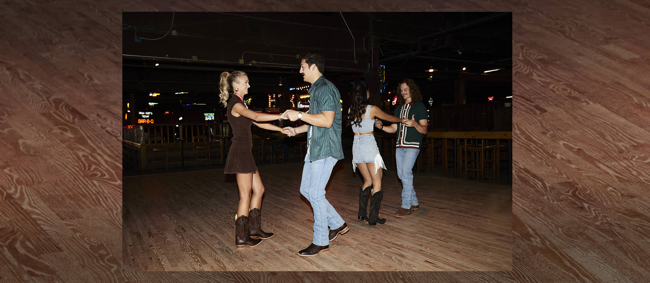 Dos parejas que llevan botas western de Justin mientras bailan.